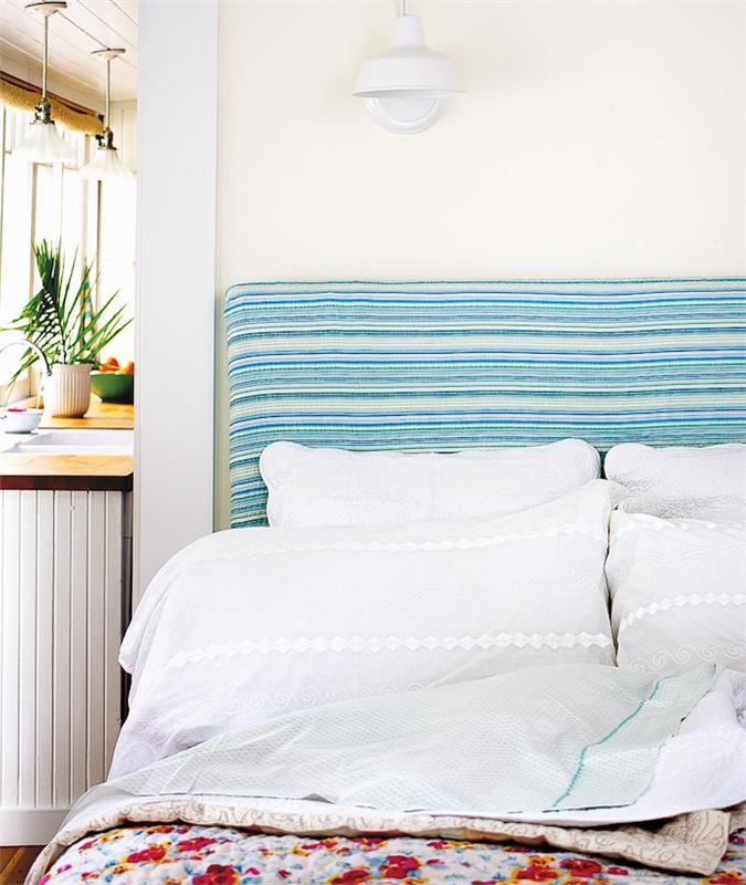 oblikovalsko vzglavje z modro -belimi črtami, belo posteljnino in prevleko za cvetlično posteljo v odprti spalnici