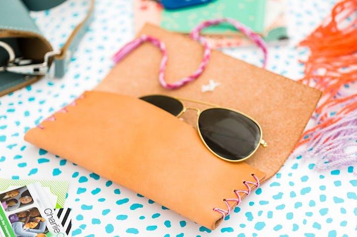 pembe dikişli deri güneş gözlüğü çantası, içinde güneş gözlüğü, düşünceli yılbaşı hediyeleri, mavi ve beyaz yüzey