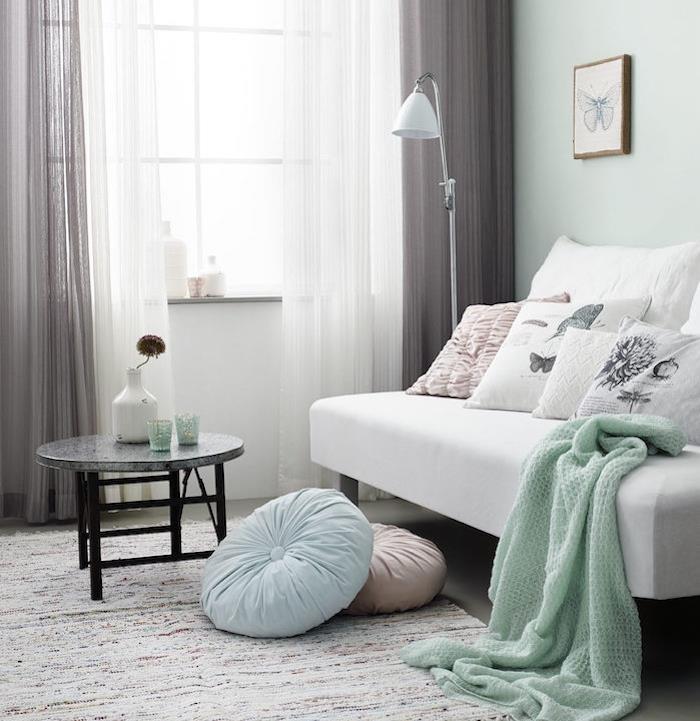 Beli kavč s sivo odejo mete, sivo -bele zavese, risba metulja v okvirju s svinčnikom, sodobna dekoracija spalnice, ideja za dekoracijo spalnice za odrasle