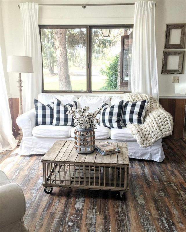 bel kavč, klubska mizica, bele zavese, črno -bele blazine, beli pleteni kariran les, lesena tla