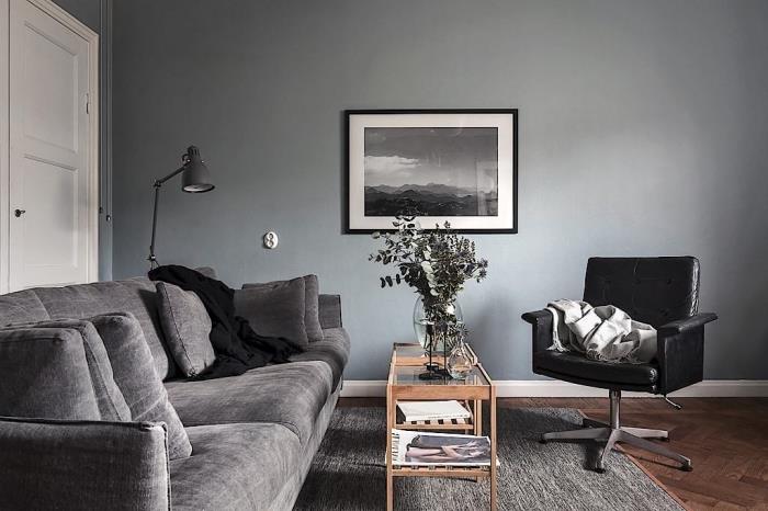 Ahşap ve cam masalı gri duvarlı bir oturma odasında davetkar bir atmosfer, minderli gri kanepe modeli