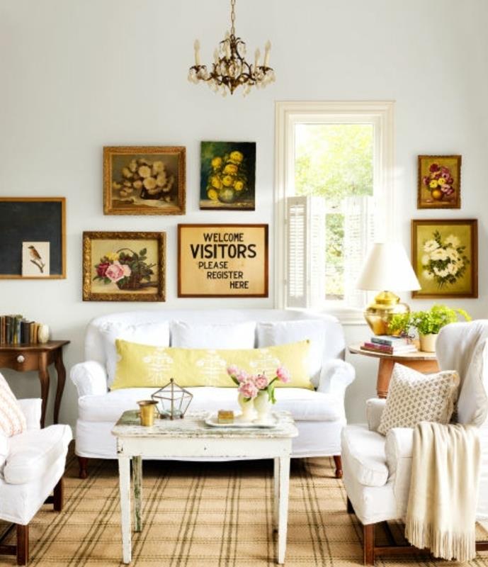 primer podeželske elegantne mize v obrabljenem lesu, cvetlični osrednji del, beli kavč in naslanjači, stenske dekoracije slik, baročni lestenec
