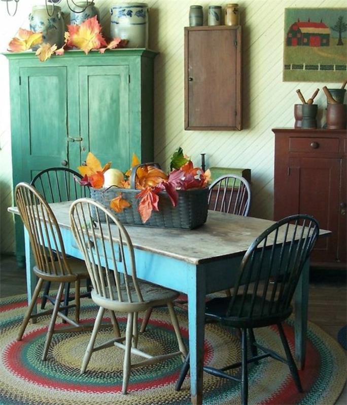 dekor podeželske hiše, miza iz surovega lesa, obrabljeni leseni stoli, pastelno zelena omara, jesenska dekoracija, staro kuhinjsko pohištvo