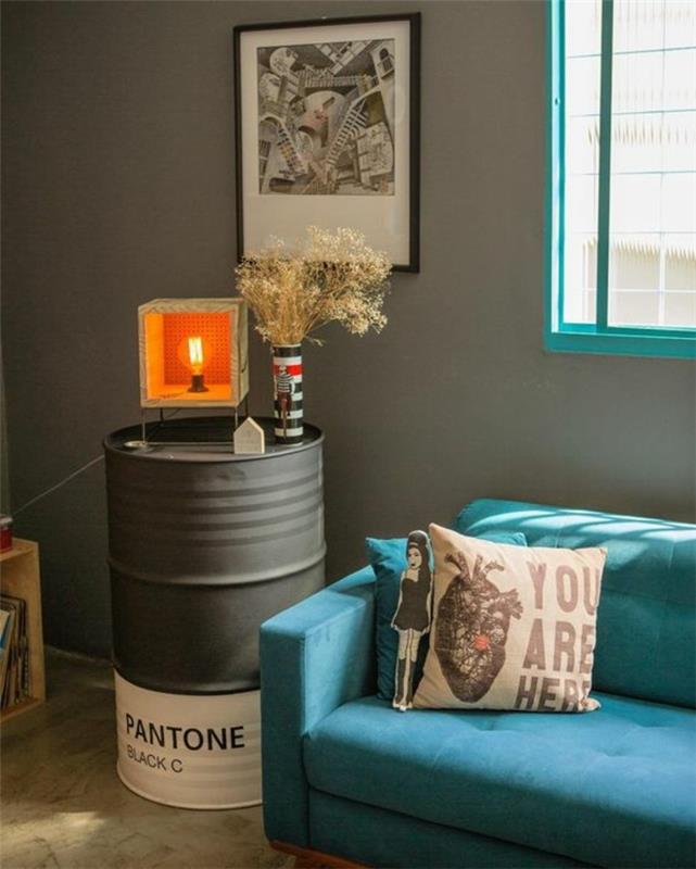 vyno statinė virto aukštu naktiniu staliuku, papuošta originalia „pasidaryk pats“ lempa, mėlyna sofa, nespalvota tapyba