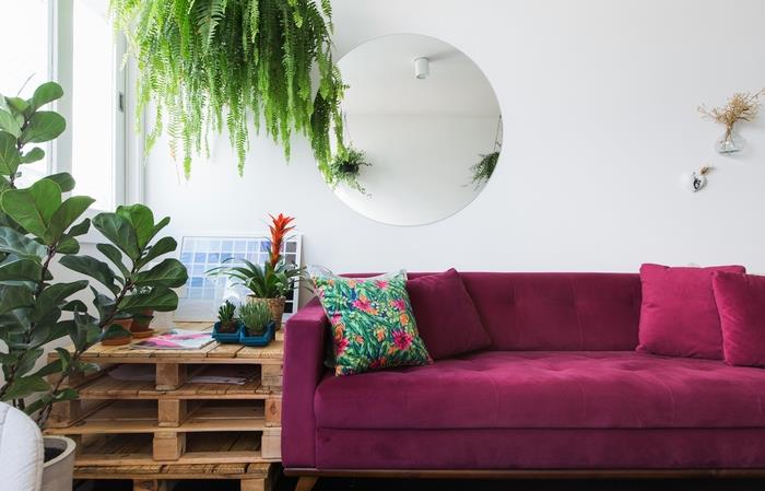 bir palet masa ve kadife bir kanepe ile tezat oluşturan tazelik dolu yeşil vurgulara sahip bir oturma odası