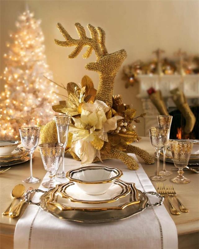 šviesiai balta eglė, šventėms dekoruotas stalas, elegantiškas stalo servisas, baltas židinys, elnio statulėlė, balto stalo bėgikas