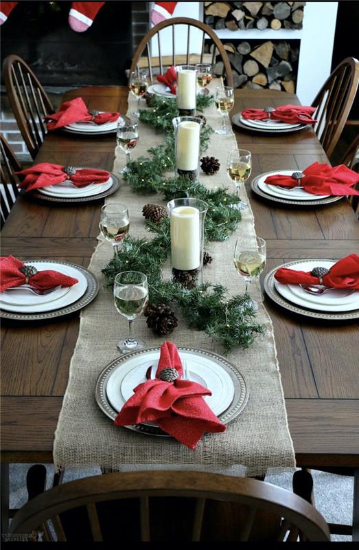 rdeče -bela božična miza z naravnimi elementi, zelena venec in borovci