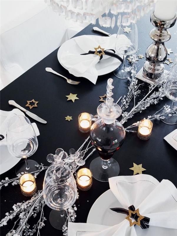 novoletna miza v črni barvi z bleščečimi elementi, kot so argentinske veje in zlate okrasne zvezde