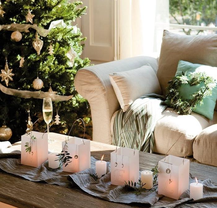 ahşap masa üzerinde mumlar ile kağıt fenerler ile gri masa koşucu, beyaz kanepe, yanında Noel ağacı, Noel masa dekorasyonu