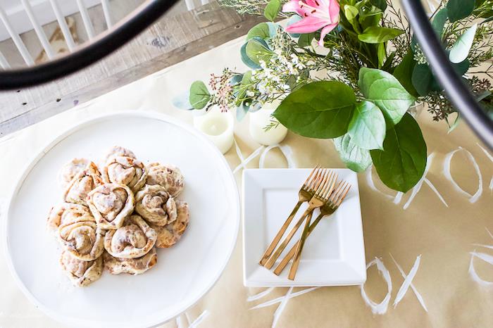 romantiškas stalas Valentino dienai su popierine staltiese ir cinamono ritiniais lėkštėje