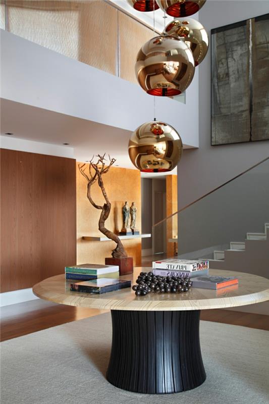 šiuolaikiškas įėjimas, apvalus stalas, pakabinamos lempos, bonzai medis, balti laiptai su stiklo siena