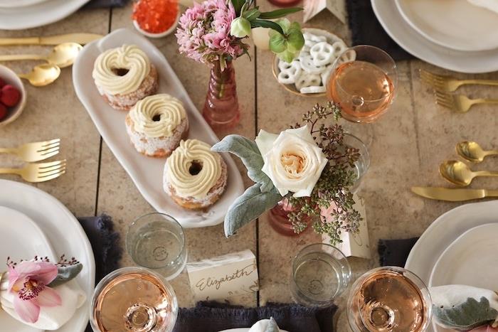Valentino dienos stalas su kepiniais ir taurėmis, užpildytomis rožiniu vynu ir padengtas auksu