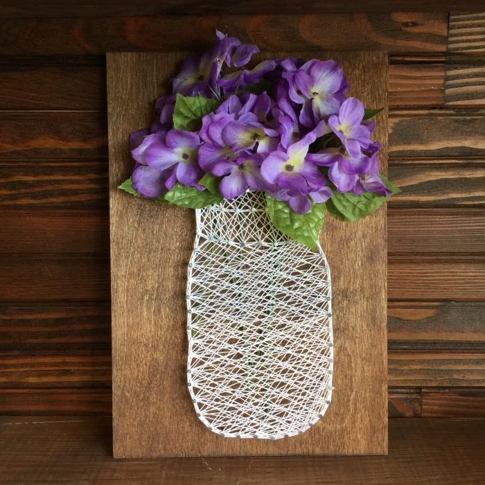 lengvas „pasidaryk pats“ raštas su tamsios medienos lenta ir baltos vielos vazos formos kūriniu su dirbtinėmis gėlėmis