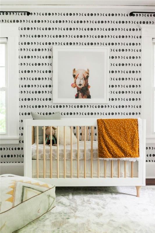 kūdikio kambario tapyba, besišypsantis kupranugaris baltame rėmelyje, juodai balta siena, balti langų rėmai, baltas ir pistacijų kilimas