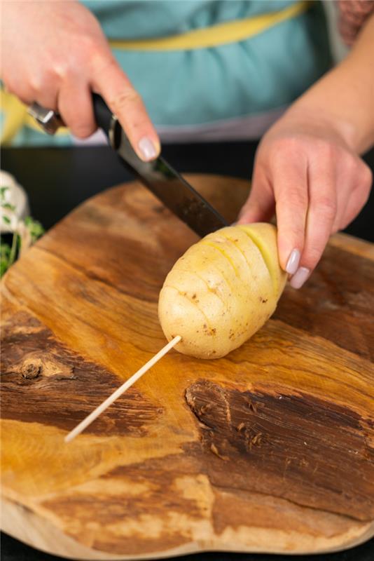 Tagliare la patata a fisarmonica, tagliere di legno con una patata con la buccia
