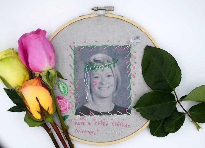 siuvinėjimo lankelis su atspausdinta meistro nuotrauka ir dekoruotas spalvotais siūlais ir siūlų karūna su rožių puokšte šalia