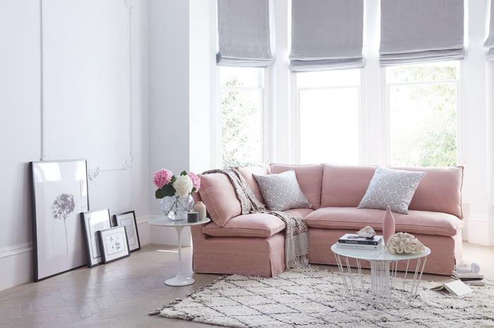 kokią spalvą susieti su pilka, dekoratyvia idėja apie stilingą svetainę su baltomis sienomis ir medinėmis grindimis, apstatytomis rožine sofa ir smėlio spalvos kilimu