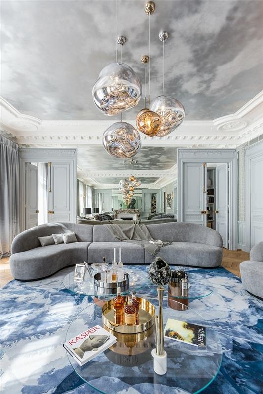 velika dnevna soba s sivim dekorjem, viseče svetilke, klubske mizice, modra preproga, originalna poslikava stropa