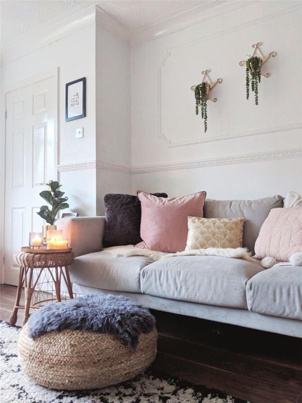 kokoniškas daniško „hygge“ interjero vaizdas, kokonavimo kampas gyvenamajame kambaryje su pilka sofa, padengta dekoratyvinėmis pagalvėmis, džiuto osmanas ir dekoratyvus šoninis stalas