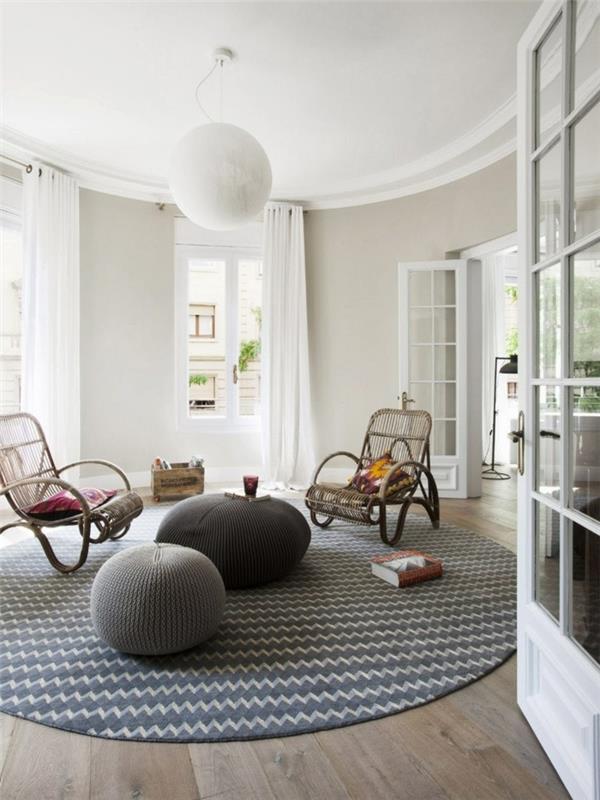 koza şeklinde oturma odası dekor fikri, ahşap parke, yuvarlak halı, gri puflar, beyaz duvarlar, hasır sandalyeler
