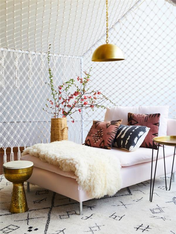 ahşap mobilyalar ve altın aksesuarlar ile beyaz bir oturma odasında egzotik dekor, makrome odası ayrımı örneği