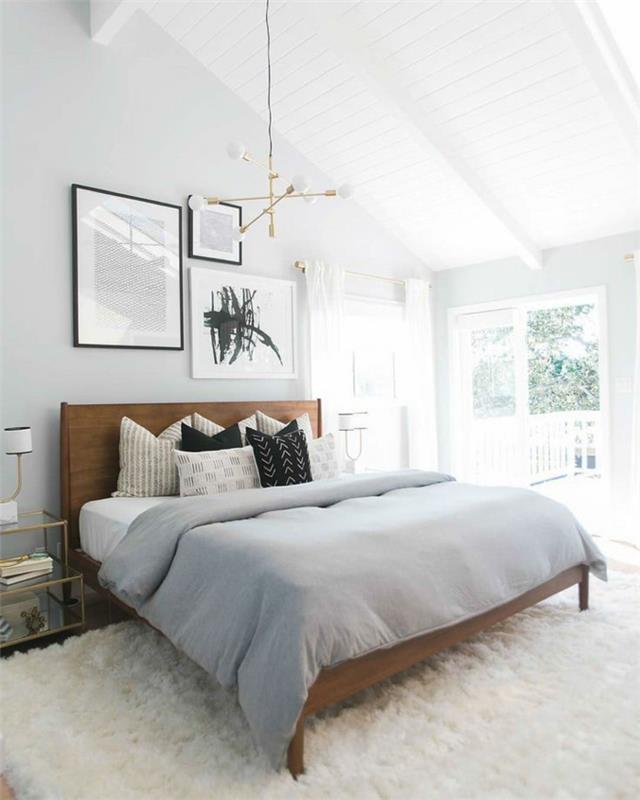 gražus baltas miegamojo dekoras, medinė galvūgalis, minkštas baltas kilimas, lemputė, baltos sienos, pilka antklodė
