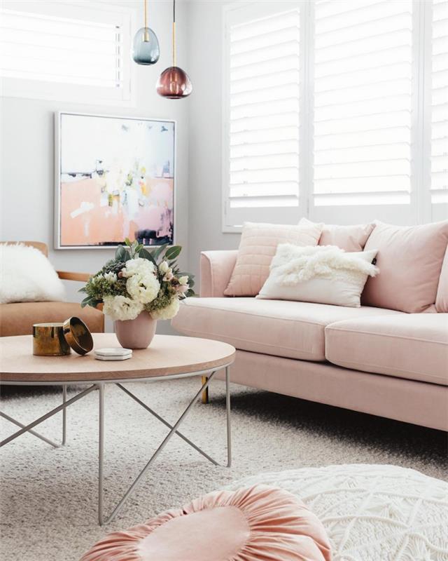 svetainės dekoras su baltomis sienomis su rožine sofa ir apvaliu mediniu kavos staliuku, stikliniu pakabinamu šviestuvu
