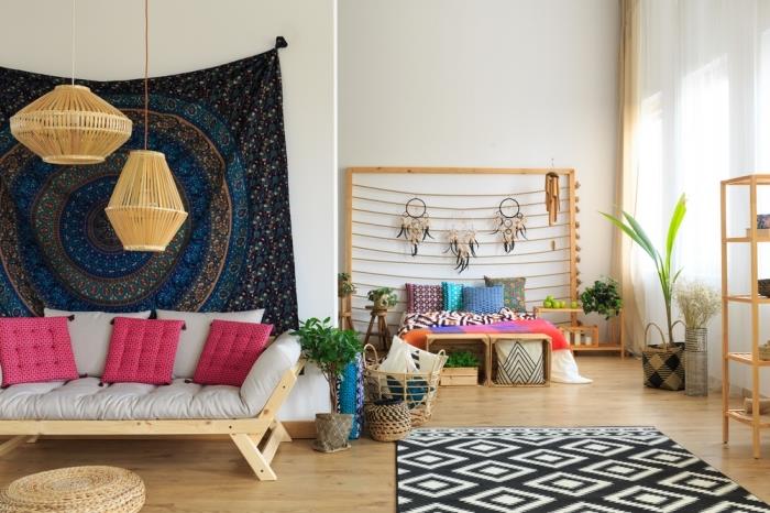 študentska namestitev z elegantnim in boemskim dizajnom, dnevna soba opremljena z lesenim pohištvom z kavčem, pokritim z roza blazinami in tapiserijo iz temnih sten
