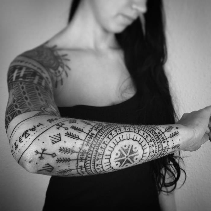 tetovaža ženska podlaket, risba s črnilom v oblikovanju mandale s puščicami in plemenskimi simboli