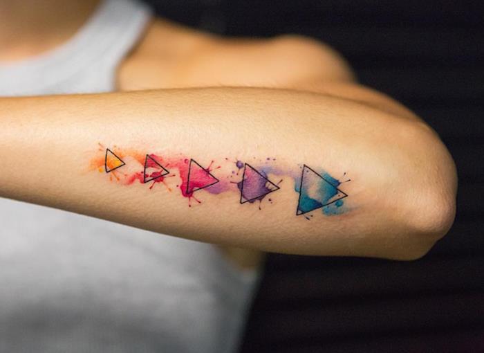 majhna ženska tetovaža podlakti s preprostimi trikotniki in akvarelnimi barvami