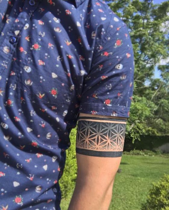 vyriškos apyrankės tatuiruotės pavyzdys, juoda juosta su gėlių raštais, paprastos gėlės, tatuiruotė su raiščiu