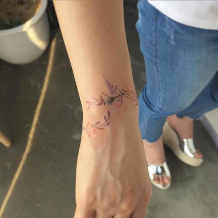 riešo apyrankės tatuiruotė moterims, spalvinga gėlių šaka aplink riešą, elegantiška tatuiruotės idėja
