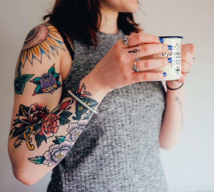pisane stare šolske tetovaže na ženski roki z rožnatimi cvetovi in ​​sončničnimi tetovažami na rami