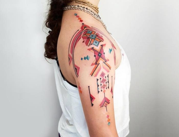 tetovirana ženska, barvna risba na rami in roki, body art z geometrijskimi vzorci in puščicami