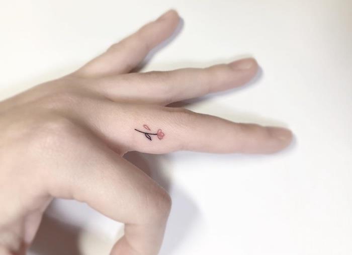 maža diskretiška tatuiruotė, padaryta ant piršto pusės, vaizduojanti spalvingą gėlę, tatuiruotės piršto moters idėja