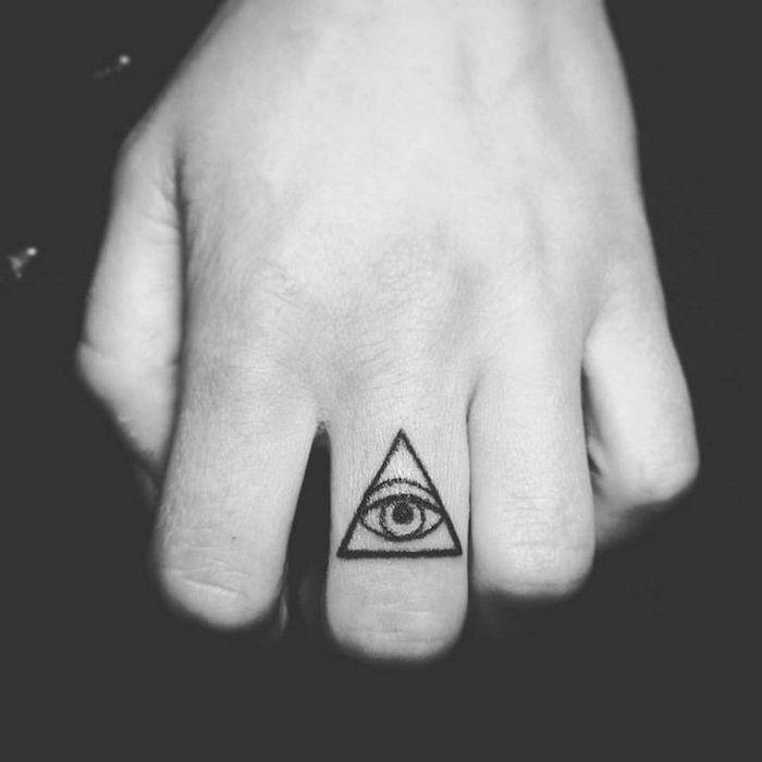 akis paslaptingai atrodančiame trikampyje, tatuiruotame ant vidurinio piršto