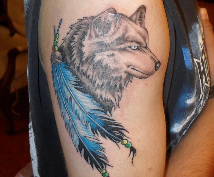 vyro tatuiruotė, piešimas ant odos vilku ir mėlynomis plunksnomis, tatuiruotė ant peties