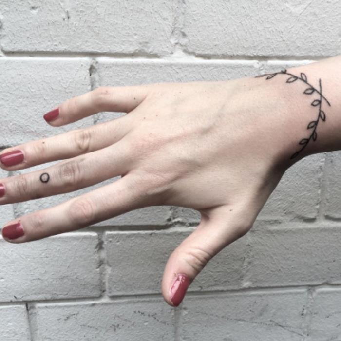 riešo apyrankės tatuiruotės idėja moterims, grafinė lapų šaka, juodas rašalas