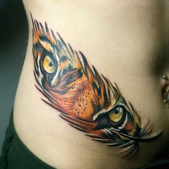 tatuiruotės idėjos moteris, piešianti ant odos dizaino plunksnomis ir tigro akimis, tatuiruotė spalvomis