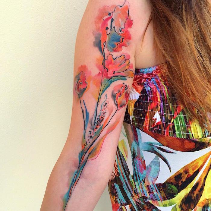 abstraktna tetovaža cvetja v akvarelnih akvarelnih barvah na ženski roki s pisano obleko