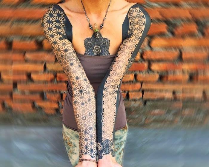 Geometrijski ženski model tetovaže na celo roko s črnimi rozetami od ramena do zapestja in tetovažo mandale na prsih
