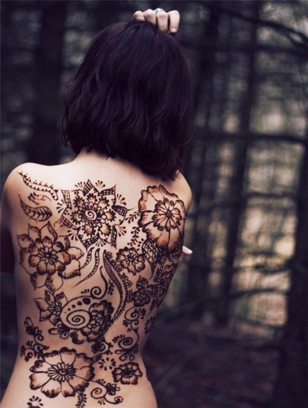 vzorec kane, ženska na hrbtu, tetovirana s kano z listi in cvetovi, ženska frizura srednje dolžine temno barvanje