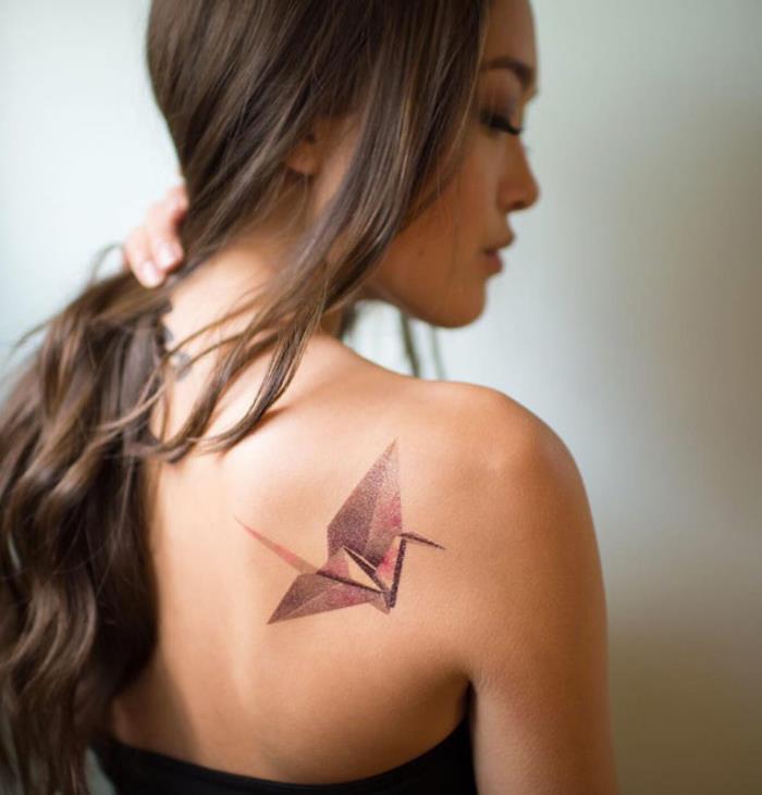 roza in vijolična geometrijska tetovaža žerjava, navdihnjena z origami umetnostjo