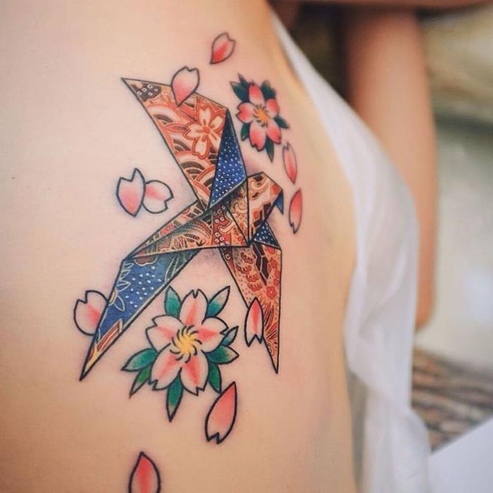 Japonski dizajn tetovaže, ki prikazuje origami golobico v barvi, povezano z majhnimi češnjevimi cvetovi