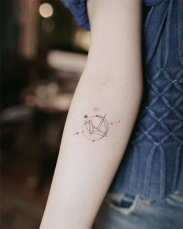 minimalistična tetovaža, ki predstavlja žerjava origami, postavljenega v središče armilarne krogle