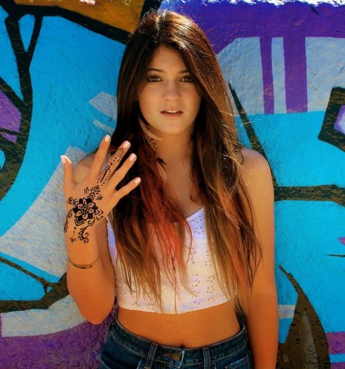 model ročne kane, dolgi kostanjevi lasje z rožnatimi odtenki, uhani z bež in črnim perjem