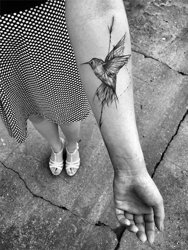ženska tetovaža podlakti, ptica in puščica, pikčasto krilo, bele sandale, majhna enobarvna tetovaža
