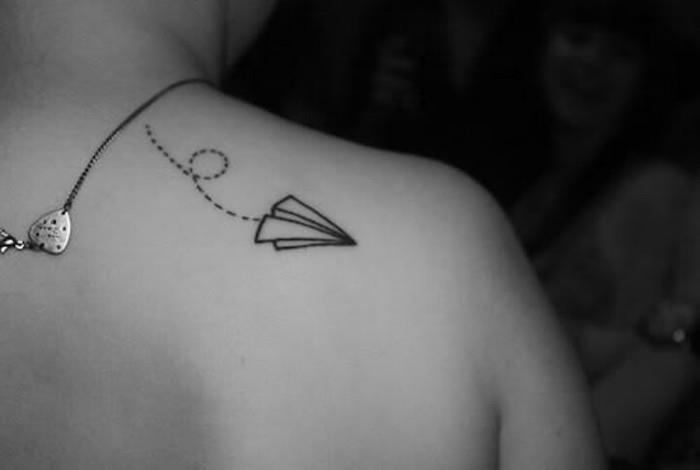 minimalistična tetovaža iz papirnatega letala na ženski lopatici