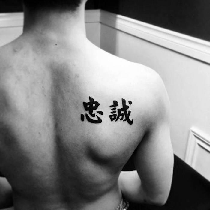 Japonų rašantis vyras tatuiruoja japoną ant kairiojo peties