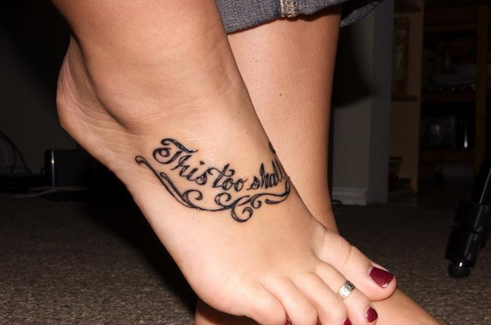 tetovaža stopal z besedilom v črnem črnilu, rdeč lak za nohte, kavbojke, ženska ideja tetovaže